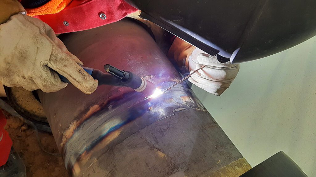 Joining two sections of a pipe together with tungsten inert gas welding.